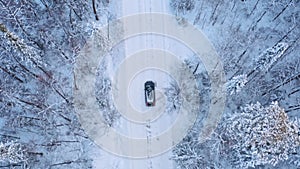 Lonely vehicle driving on road in winter forest