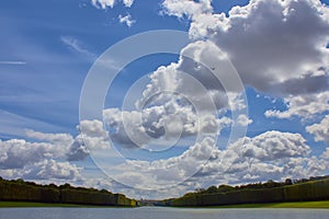 A lonely view of Versailles park, France. The geometric combination of green trees, grass areas and Grand Canal