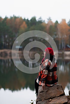 Lonely vivid girl surrounded by a lake and autumn woods.