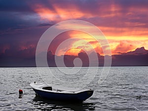 Lonely white and blue sea motor boat and red buoy on water surface side view on sunset