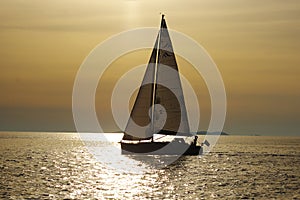 Lonely white sail at infinite ocean on a sunset