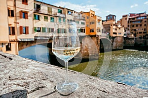 Lonely white wine glass in distance from people, past famous bridge of Florence, Italy. Empty european city