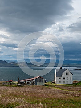 Lonely White Wooden House at coastline in East Iceland with panoramic view and stormy sky