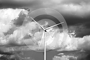 Lonely wind turbine. Stormy sky background. Black and white photography.