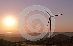 Lonely wind turbine with sun setting on the background