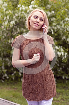 The lonely woman in a beautiful knitted jacket. The beautiful woman on walk. Fashionable clothes.