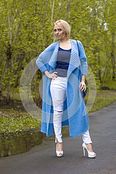 The lonely woman in a beautiful knitted jacket. The beautiful woman on walk. Fashionable clothes.