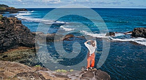 Lonely woman dressed light summer clothes enjoying Indian ocean view with strong surf on cliff at Gris Gris viewpoint extreme photo