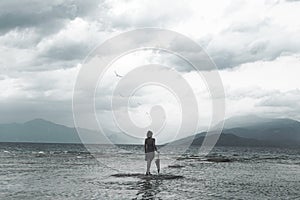 Lonely woman looks at infinity and uncontaminated nature on a stormy day