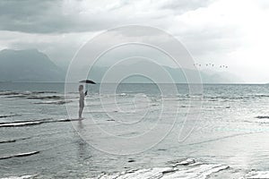 Lonely woman looks at infinity and uncontaminated nature on a stormy day