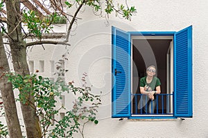 Lonely woman looks out of the window during quarantine