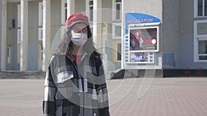 A lonely woman in a medical protective mask in a deserted city. Virus epidemic in the city. Coronavirus.