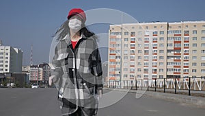 A lonely woman in a medical protective mask in a deserted city. Virus epidemic in the city. Coronavirus.