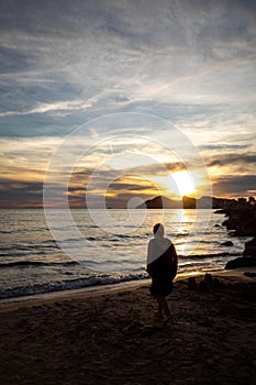 Lonely woman reflecting on love on a very special day while watching the sunset on the shore of the