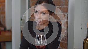 Lonely woman sit in cafe with glass of wine and looks around