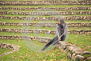 Lonely woman sitting alone on the stones into the autumn garden