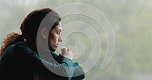 Lonely woman sitting indoor on windowsill in gloomy weather