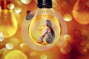 Lonely woman sitting inside light bulb looking at butterfly