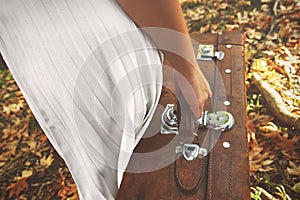 Lonely woman with a suitcase walking in the forest an autumn day