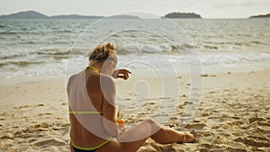 Lonely woman in swimwear on the beach drinks alcohol. Parting lo