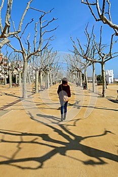 Lonely woman walking across a nice promenade on a sunny winter morning in Calella de la Costa, Maresme Seaside, Catalonia, Spain photo