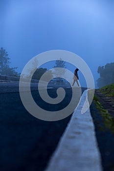 Lonely woman walking on mountain foggy highway