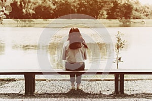 Lonely women sitting at bench alone in the park back view