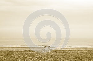 Lonely wood pier in beach with calm sea at sunset with sepia effect