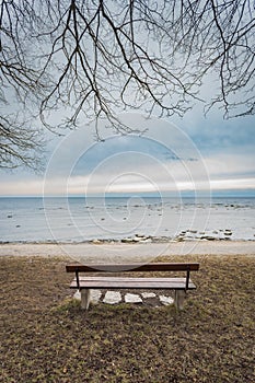 Lonely wooden bench on the autumn sea with cloudy sky