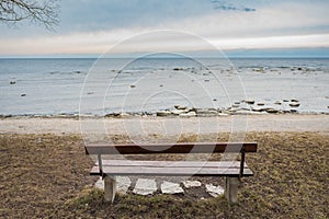 Lonely wooden bench on the autumn sea with cloudy sky