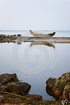 Lonely Wooden fishing boat anchored on the beach sand reflection in backwaters