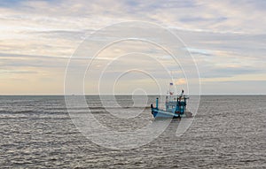 A lonely wooden fishing boat returns to the village after night catching at dawn