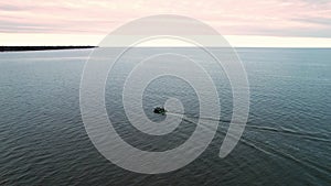 Lonely wooden motorboat floats on the blue sea to the shore