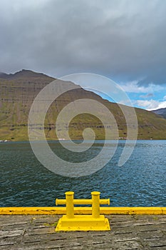 Lonely yellow dock at Seydisfjordur, and beautiful fjords around, Iceland, summer