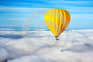 A lonely yellow hot air balloon floats above the clouds. Concept leader, success, loneliness, victory
