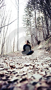 Lonely Young Girl Sitting on the ground of a path in the forest