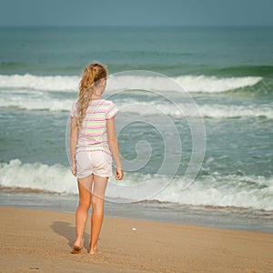 Lonely young girl walking on the beach