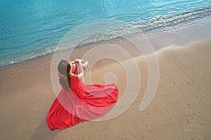 Lonely young woman sitting on ocean sandy beach by seaside enjoying warm tropical evening