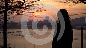 Lonely young woman standing alone on lake shore enjoying warm evening. Wellbeing and relaxing in nature concept.