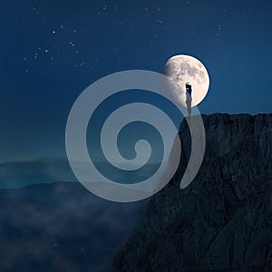 Lonely young woman on top of a cliff at night photo