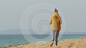 Lonely young woman walking on desolate sandy beach