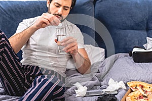 loner having headache with hangover and putting pill into glass of water