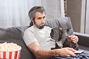 loner watching tv with with bulldog on sofa in living photo