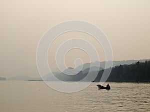 Lonesome scene of fisherman on old boat with landscape seascape estuary panorama view