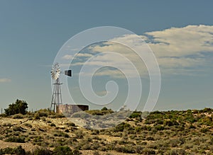 A lonesome windmill and dam on a small rise