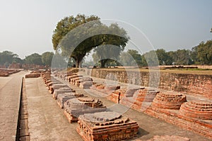 Long alley with brick monuments in archeological site with ruins of Buddhist monastery