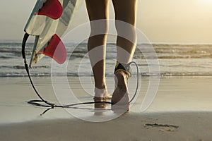 Long angle of surfer walking along beach with ankle leash and board fins