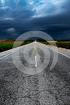 Long asphalt road between fields