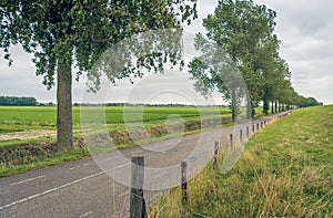 Long asphalt road at the foot of a Dutch dike