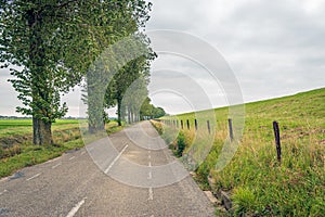 Long asphalt road at the foot of a Dutch dike